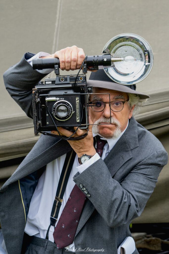 A cartoonized image of a 1940s photographer, characterized by exaggerated features and vibrant colors. The photographer is depicted holding a classic camera, wearing period-appropriate clothing such as a fedora and a suit, with a playful expression that captures the spirit of the era.